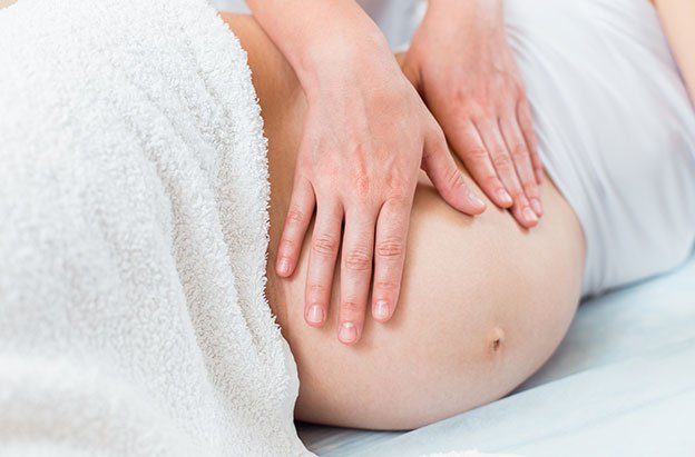 a pregnant woman getting a prenatal massage on her stomach